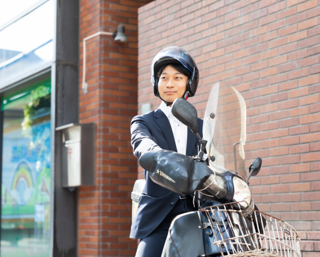 バイクでお客さまを訪問する渉外担当者